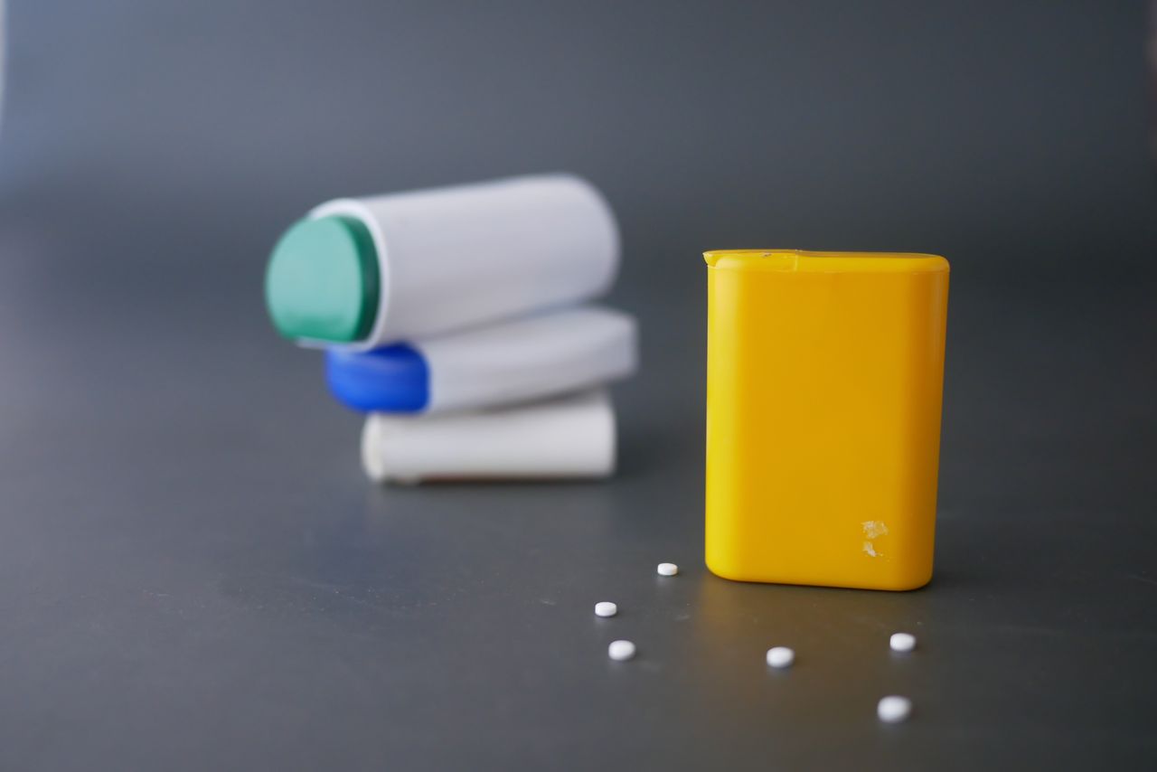 Close-up of plastic pharmaceutical containers and pills on a grey surface.